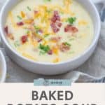 A piping hot bowl of creamy baked potato soup topped with shredded cheese and crispy bacon bits.