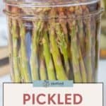 A glass jar brimming with pickled asparagus spears, sporting a label that proudly reads "Pickled Asparagus.