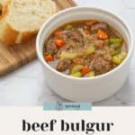 A bowl of hearty beef bulgur soup with diced vegetables, accompanied by slices of bread on a wooden board. Text reads "beef bulgur soup" and "quick & easy recipe" at the bottom.