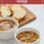 Two white bowls of easy beef bulgur soup with vegetables sit on a marble surface, accompanied by a wooden board holding slices of bread in the background. A label at the top reads "Easy beef bulgur soup.