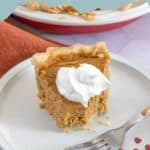 A slice of butternut squash pie topped with whipped cream sits on a plate with a fork, delightfully capturing the essence of homemade comfort. The words "Butternut Squash Pie" are elegantly written at the top of the image.