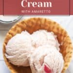 A bowl with two scoops of cherry ice cream with amaretto in a waffle bowl sits invitingly. The text reads: "Cherry Ice Cream with Amaretto" and "stetted.com". Indulge in this treat after a summer BBQ featuring roasted corn salad, blending flavors for an unforgettable meal.