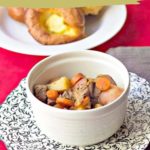 Bowl of classic beef stew with carrots and potatoes on a patterned plate, resting on a red and gray cloth. Yorkshires sit invitingly in the background. Text: "Classic Beef Stew, Easy to Make Recipe.