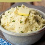 A delightful bowl of celery root mash, crowned with a pat of butter and a sprinkle of fresh herbs.