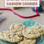 A plate of delightful salted caramel cashew cookies rests on the table, surrounded by baking supplies that hint at the craft behind these delicious treats.