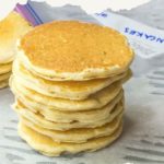 A neatly stacked pile of pancakes, topped with a label reading “How to Freeze Pancakes,” sits invitingly on a textured surface.