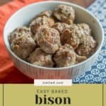 A bowl of savory baked bison meatballs rests on a table adorned with a vibrant red cloth and a blue patterned napkin.