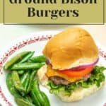 Savor a delicious bison burger with lettuce, tomato, and onion atop a soft bun. Accompanied by vibrant green peas on a white plate, this dish is a culinary delight. Text reads "How to Make Ground Bison Burgers.