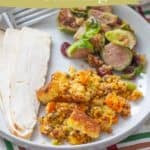 A white plate with chorizo cornbread stuffing, sliced turkey, and Brussels sprouts. Text on image reads: "chorizo cornbread stuffing www.stetted.com.