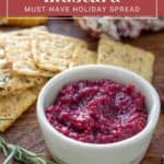 A small white bowl filled with cranberry mustard sits on a wooden surface near some crackers. Text reads: "Cranberry Mustard: Your Must-Have Holiday Spread.