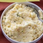 A bowl of mashed rutabaga mixed with parmesan cheese, garnished with herbs, and a spoon in it. Text reads "mashed rutabaga" and "with parmesan", with website stetted.com at the bottom.