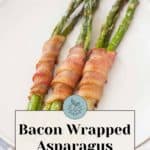 Savor the simplicity of three bacon-wrapped asparagus spears elegantly arranged on a white plate, with a text label promising "Bacon Wrapped Asparagus ready in minutes.