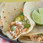 Close-up of slow cooker chicken tacos topped with sliced jalapenos, cilantro, and lime wedges. The text reads "slow cooker chicken tacos" and "easy hands-off recipe" with a website link at the bottom.