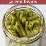 A jar filled with homemade pickled green beans. The label on the image reads "Tangy Pickled Green Beans.