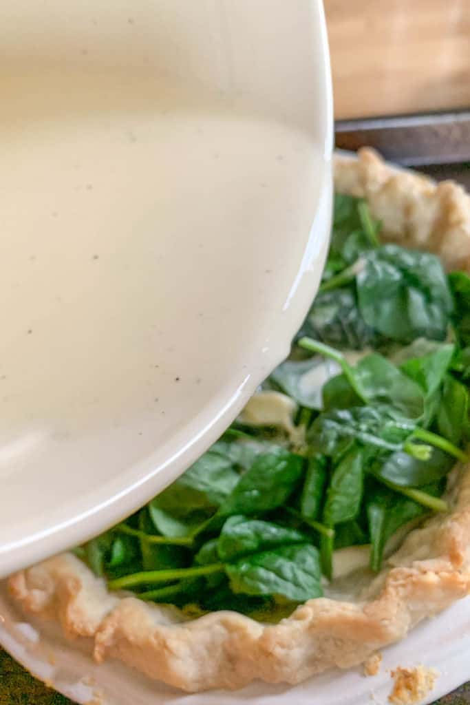 pouring egg mixture into quiche crust