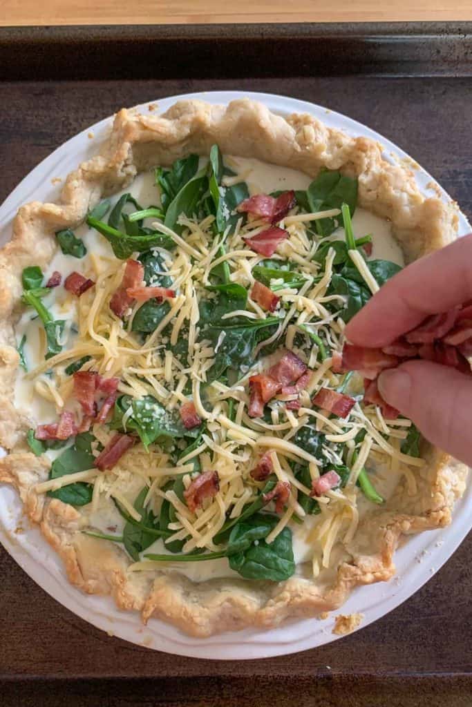 adding bacon to top of bacon spinach quiche