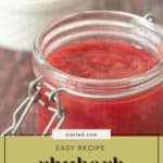 A jar of tangy rhubarb sauce sits on a wooden table, its vibrant hue contrasting with the blurred background. Text reads: "stetted.com Easy Recipe Rhubarb Sauce.