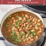 A pot filled with borracho beans, garnished with chopped cilantro, sits on a table next to a slow cooker. The top of the image reads, "Borracho Beans: Easy Slow Cooker Recipe.