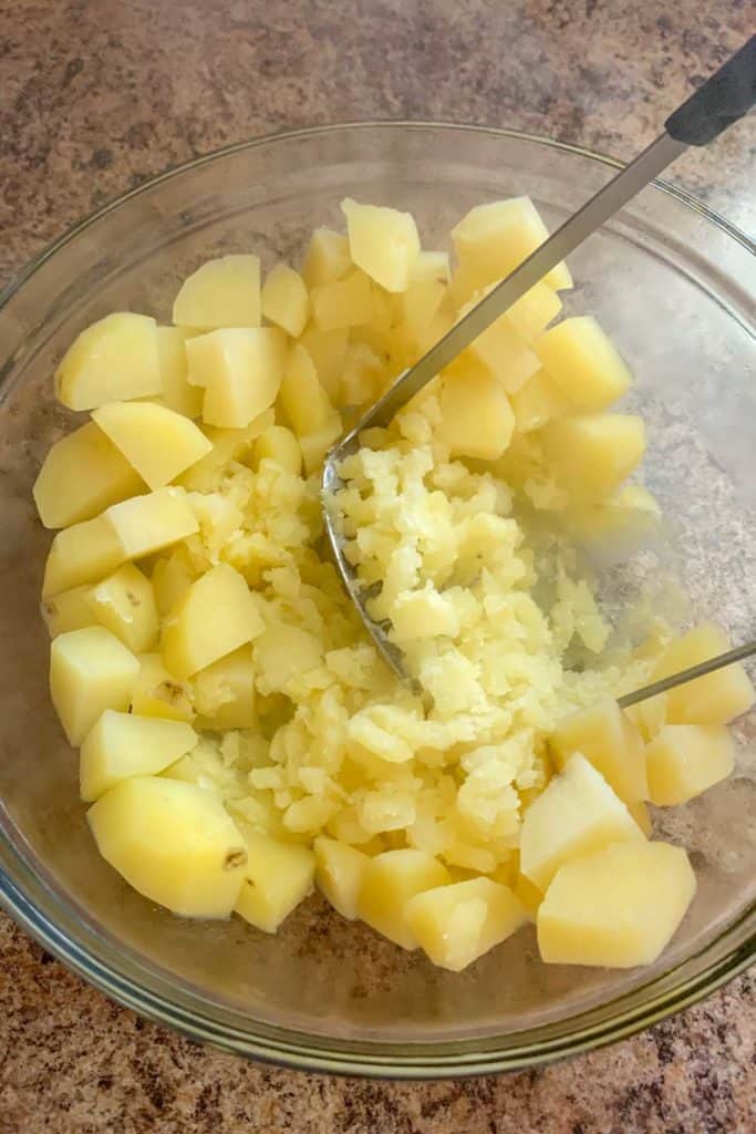 mashing potatoes in a bowl