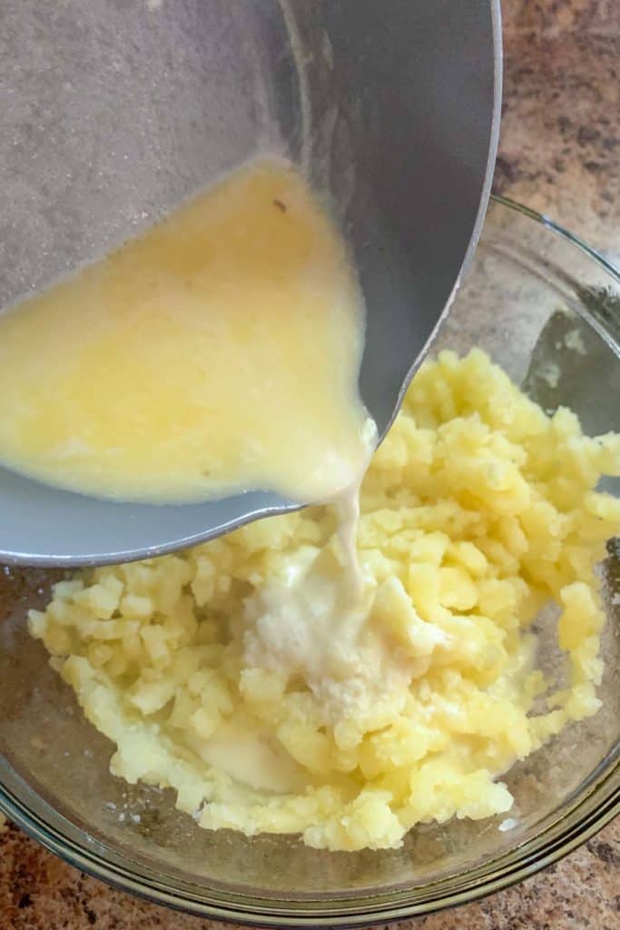 adding cream and butter to mashed potatoes