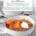 A bowl of savory butternut squash chili topped with creamy sour cream sits on a charming checkered cloth. Text above announces: "Easy to Make Recipe: Butternut Squash Chili.