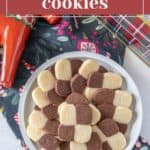 A plate of checkerboard cookies arranged in a checkerboard pattern, featuring alternating light and dark squares, placed on a festive fabric. Text above the image reads, "checkerboard cookies.