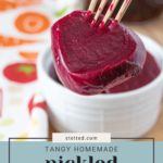 A fork holds a slice of tangy pickled beet over a white dish, set against a vibrant cloth backdrop. Text on image: "Tangy Homemade Pickled Beets" and "stetted.com".