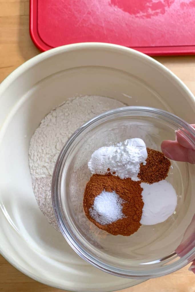 Adding dry ingredients for muffin batter into a mixing bowl.