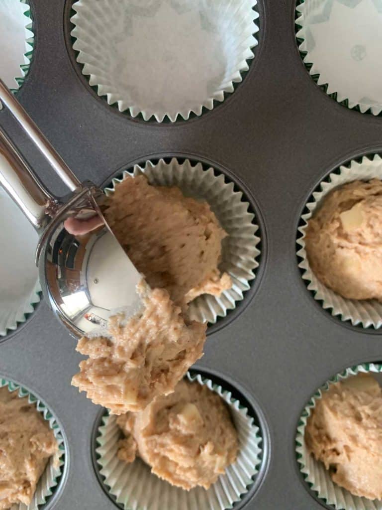 Scooping muffin batter into a muffin pan.