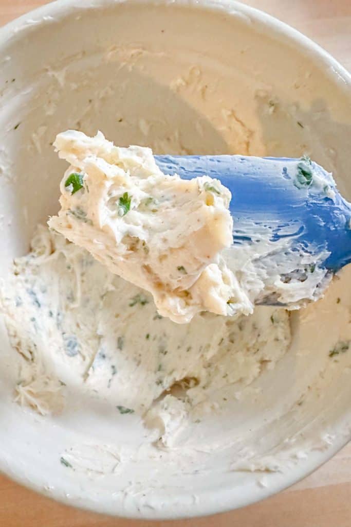 Garlic butter in a bowl mixed together with some held up for show with a spatula.