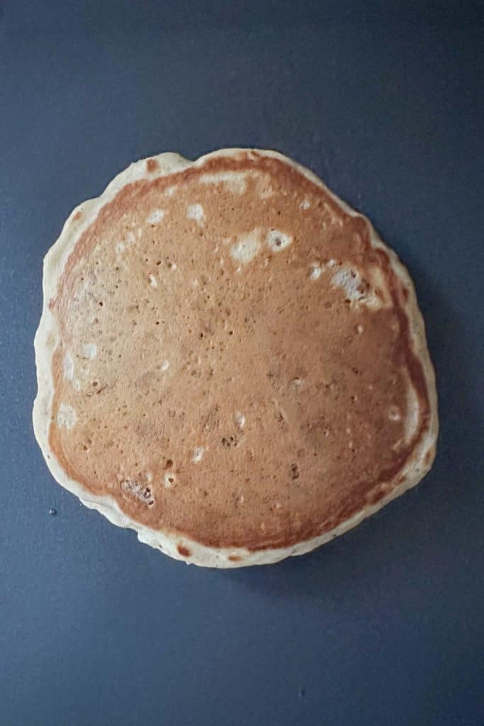 Pecan pancake cooking on an electric griddle.