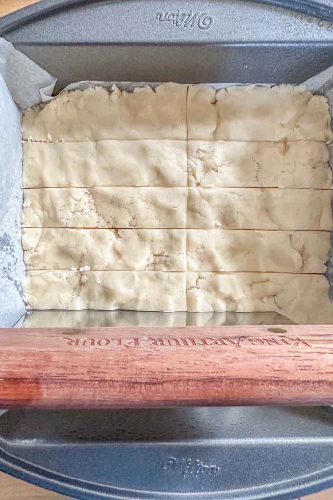 Cutting into unbaked shortbread dough in pan.