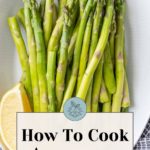 A plate of fresh asparagus with a lemon wedge beautifully illustrates the art of how to cook asparagus.