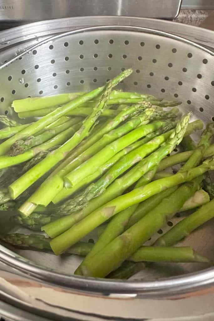 Steamed asparagus in a steamer pot.