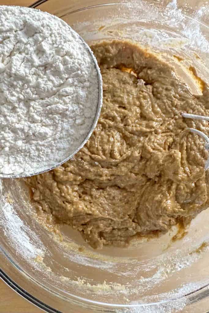 Adding more flour to bread dough in mixing bowl.