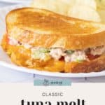 A close-up of a classic tuna melt sandwich with melted cheese and vegetables on toasted bread, served alongside crispy potato chips on a white plate.