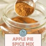 A teaspoon of apple pie spice held over a small glass jar. Text on the image reads, "Apple Pie Spice Mix for fall baking. Get the recipe at stetted.com.