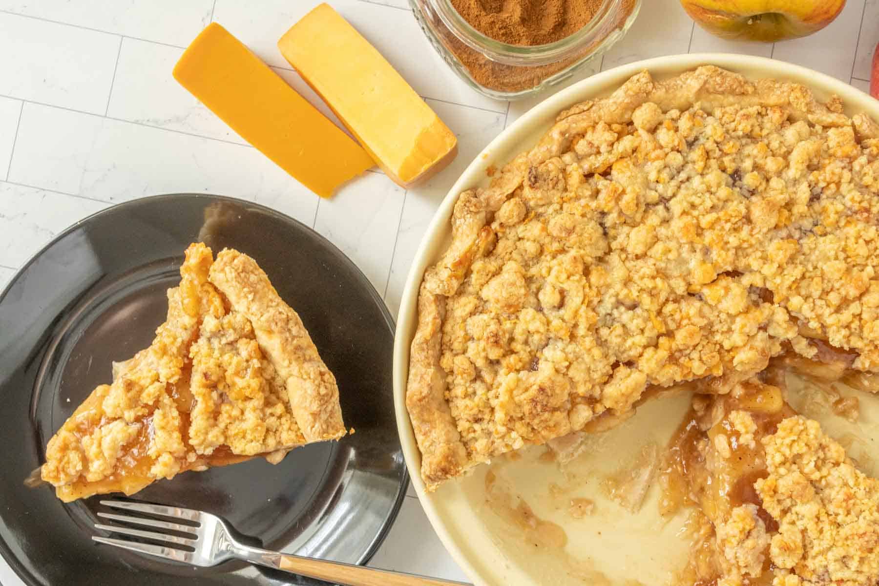 A slice of apple pie on a plate with a fork.