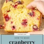 A hand holds a delightful slice of cranberry orange bread, with a freshly baked loaf and the guide "How to Make Cranberry Orange Bread" visible in the image.