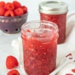 Raspberry jam in a jar with a spoon.