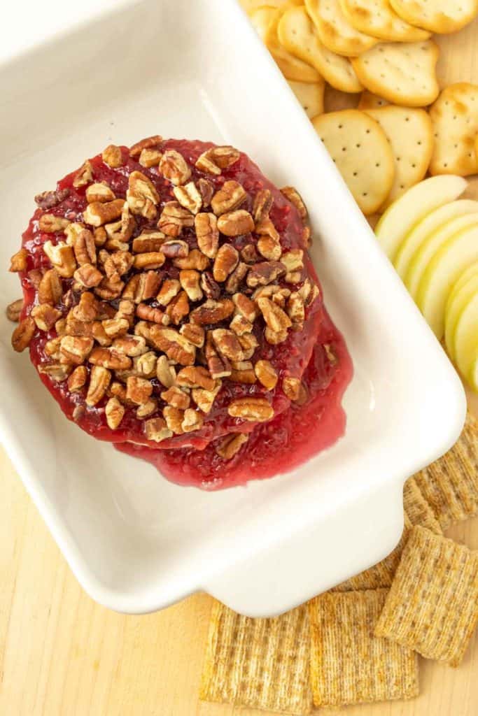 Baked brie with jam with crackers on a white plate.