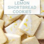 A delightful pile of lemon shortbread cookies with icing and zest graces a wooden surface.