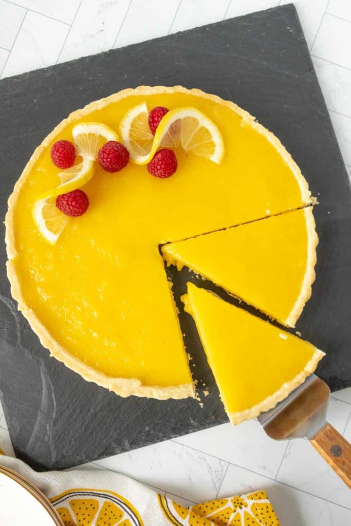 A lemon tart with a slice taken out of it.