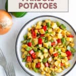 A bowl of diced parboiled potatoes mingles with vibrant red and green bell peppers, elegantly arranged on a white surface beside onions and forks. Text reads, "Learn how to parboil potatoes.