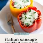 Two bell peppers, one red and one yellow, are transformed into Italian stuffed peppers with savory sausage filling, topped with melted cheese and fresh herbs. Served on a white plate with a fork, the image promotes a cherished family recipe.