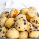 A rectangular tray filled with a stack of mini blueberry muffins on a white surface.