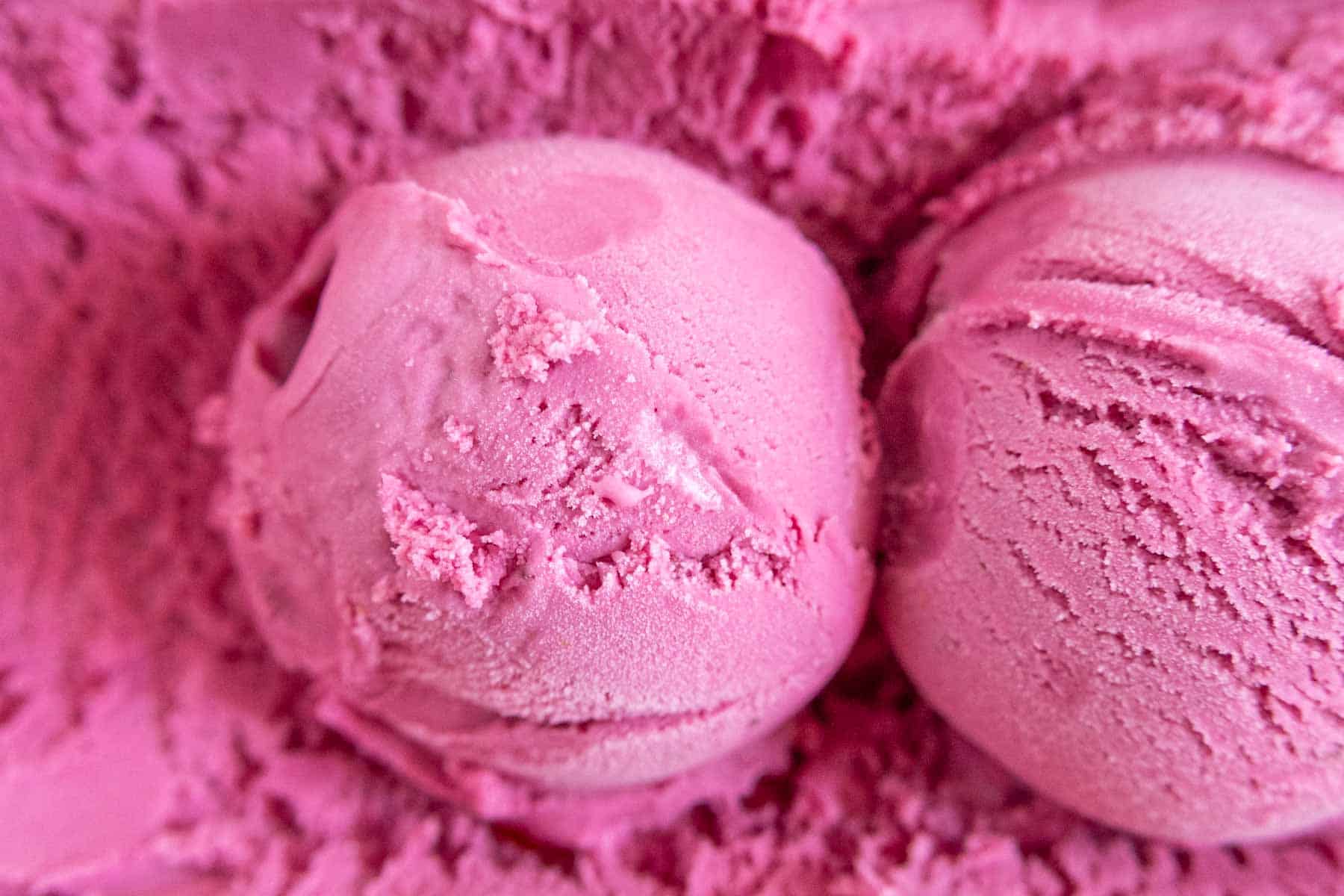 Close-up of two scoops of pink ice cream with a smooth, creamy texture.