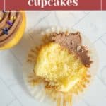 A partially eaten cupcake with chocolate frosting sits on a white surface, accompanied by the text "classic birthday cupcakes," capturing the essence of these delightful birthday treats.