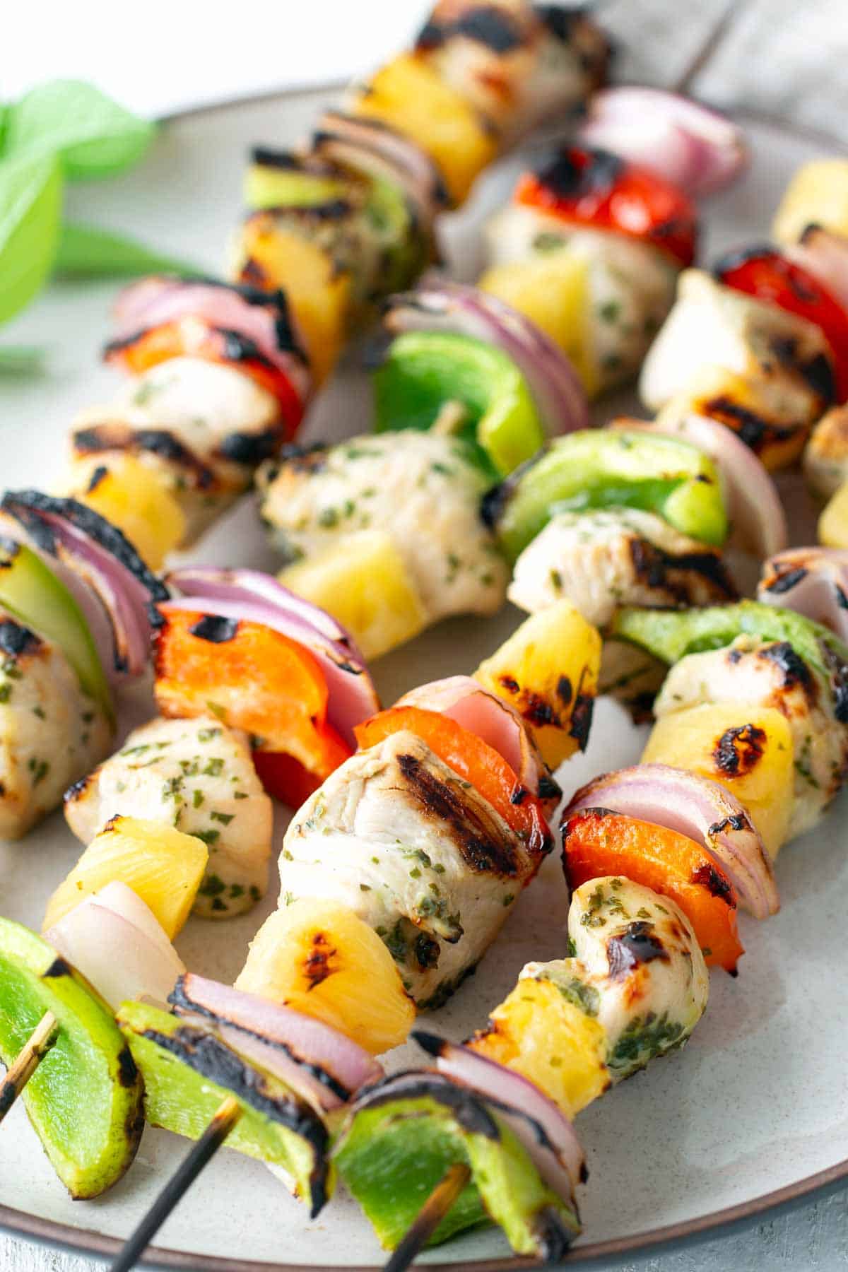 Grilled chicken skewers with colorful vegetables and pineapple chunks, arranged on a plate.