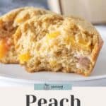 Close-up of a peach muffin cut in half to show its moist interior, placed on a white plate. Text overlay at the bottom reads "Peach Muffins" with a small logo above the text, perfect for your next birthday cupcakes.